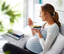 Mujer en embarazo comiendo un plato de frutas 
