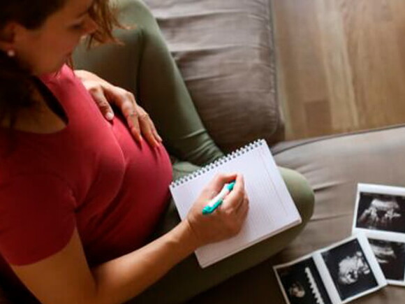 Mamá con un cuaderno mirando la ecografía de su embarazo múltiple. 