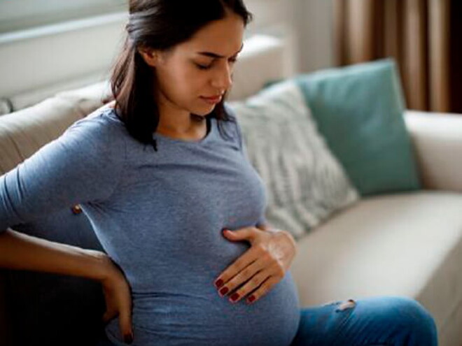 Mamá tocando el vientre y la espalda sintiendo molestia.