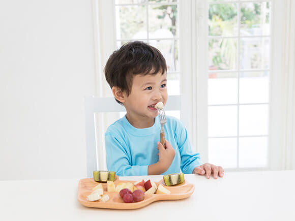 Un niño comiendo fruta en la cocina.