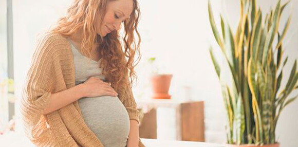 Mujer tocando su vientre de embarazo múltiple.