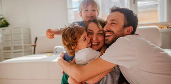 Papá y mamá abrazando a sus hijos.