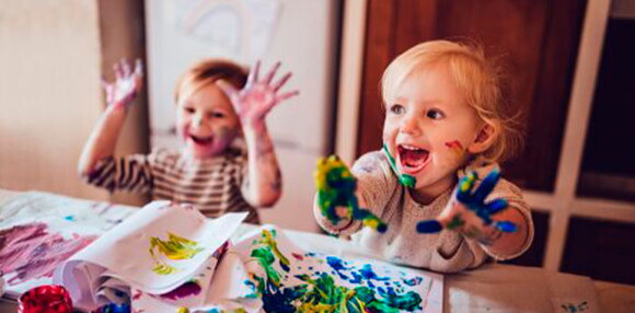 Niños pintando con pintura y riendo.