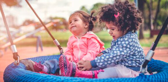 Dos niñas en el parque jugando.