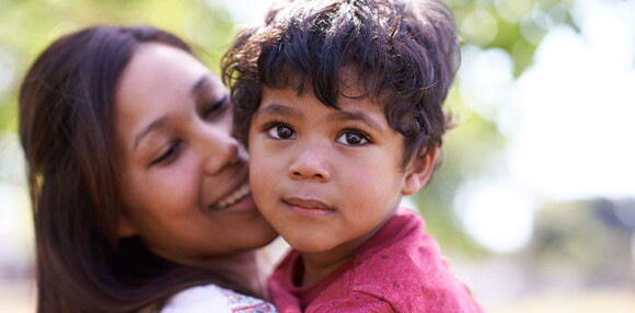 Mamá alzando a su niño sonriente.