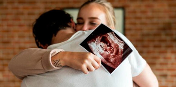 Pareja abrazados celebrando que tendrán un niño arcoíris